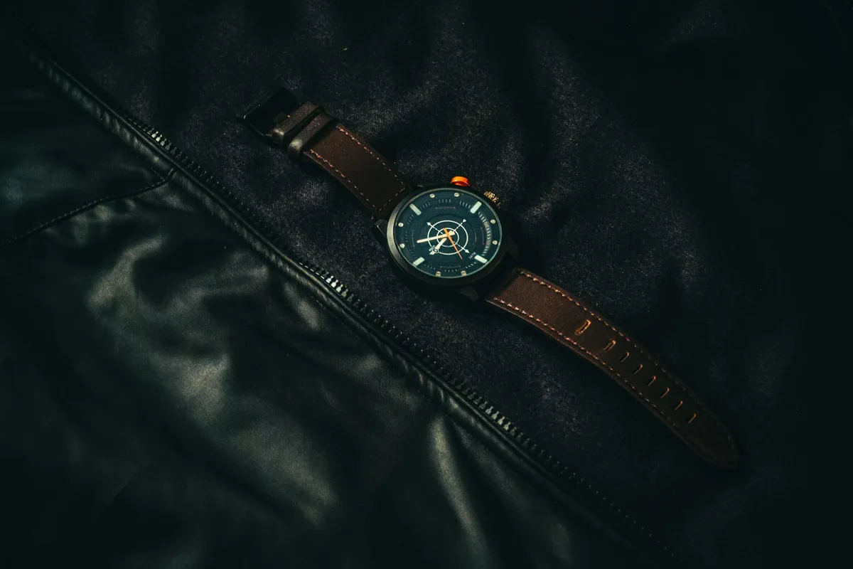 Wristwatch with a brown leather strap resting on a dark leather jacket