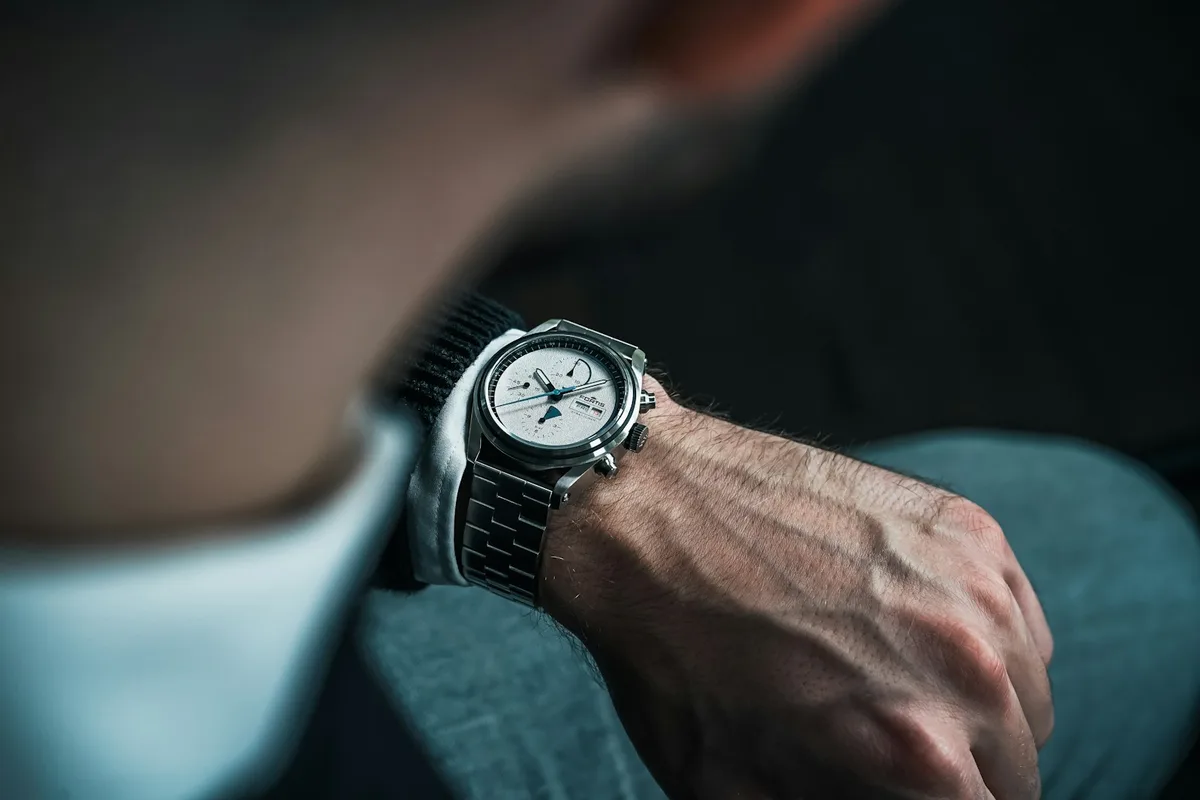 Man in a dark sweater checking a stainless steel wristwatch on his wrist