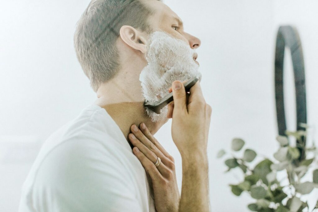Man carefully shaving his neck in front of a mirror