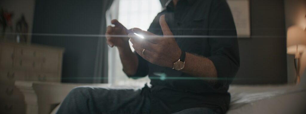 Man using a smartphone late at night in a dark bedroom