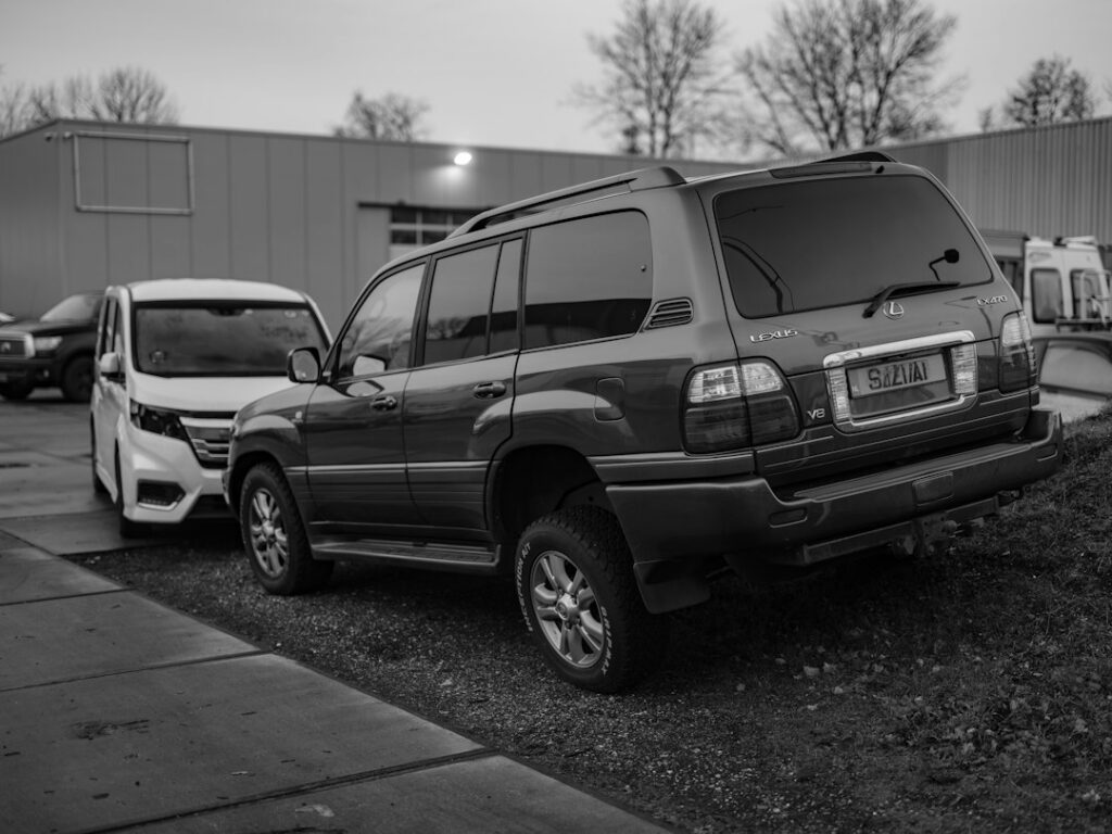Buyer checking a used car listing on a phone beside the vehicle