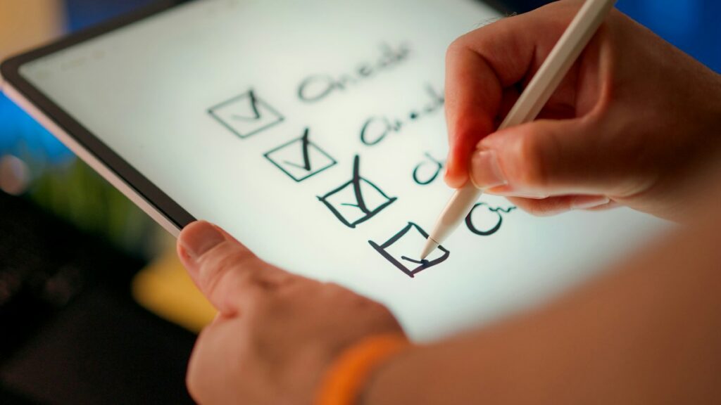 Hand checking tasks on a digital checklist displayed on a tablet