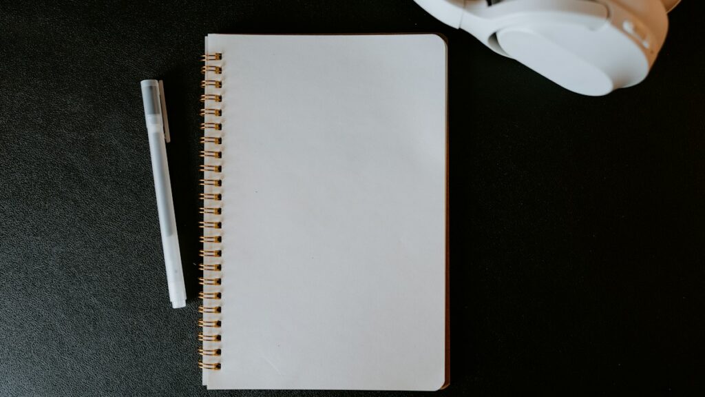 Notebook with pen and headphones on a desk