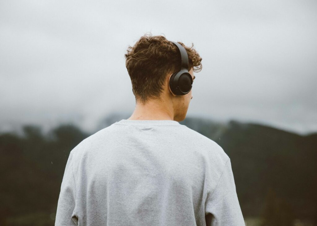 Man adjusting headphones while thinking about hearing health