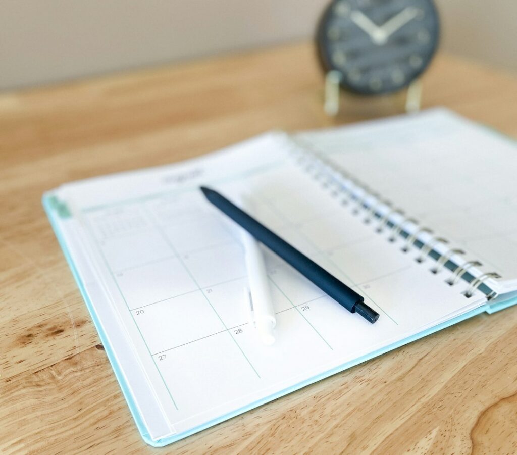Time blocked work schedule beside a notebook and laptop