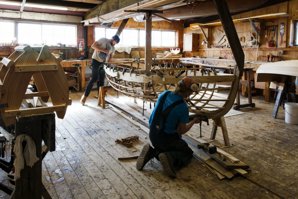 Craftsmen building a wooden boat in a traditional workshop