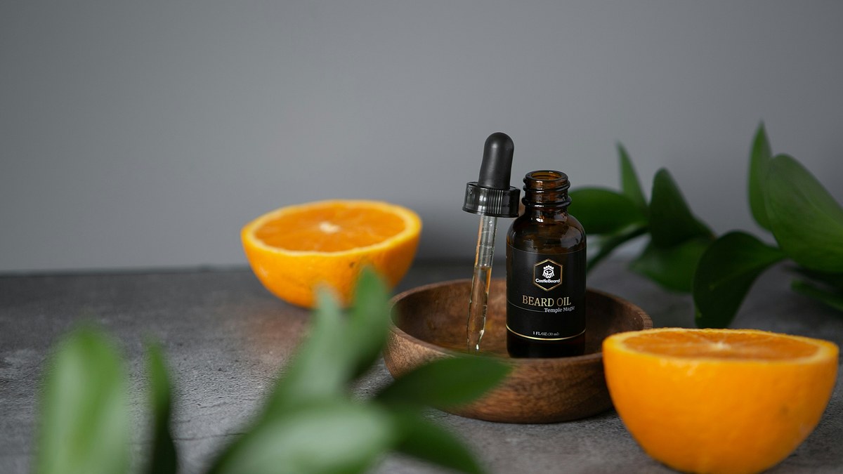 Beard oil bottle beside orange slices and greenery