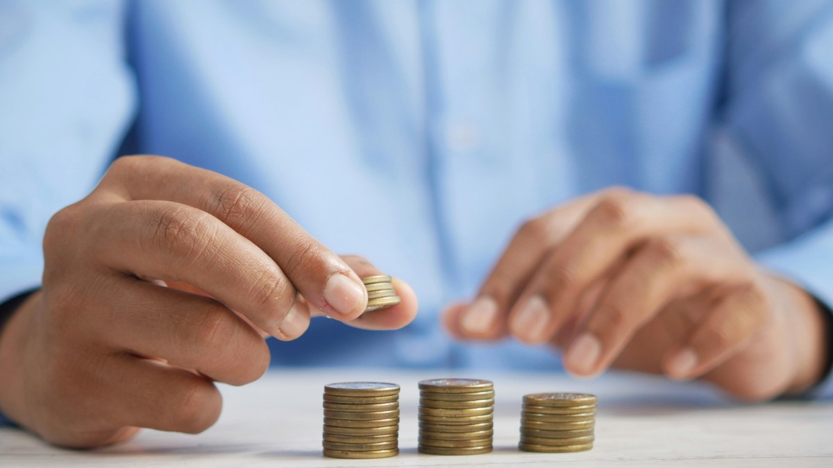 Hands adding coins to small stacks on a table