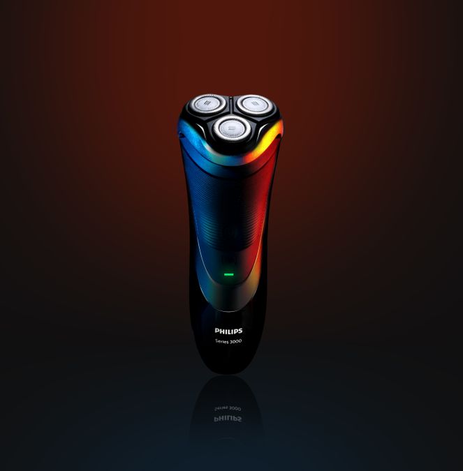 Three-head rotary electric shaver in blue and red studio lighting