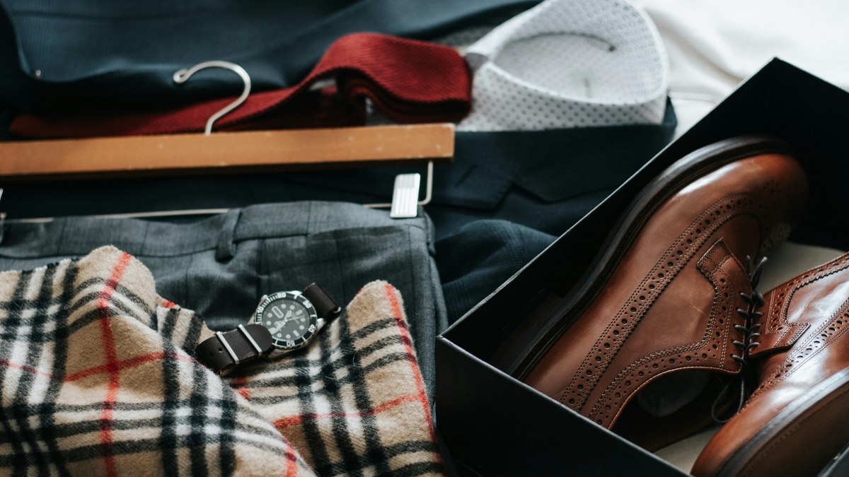 Men's shoes, belts and folded clothes arranged together