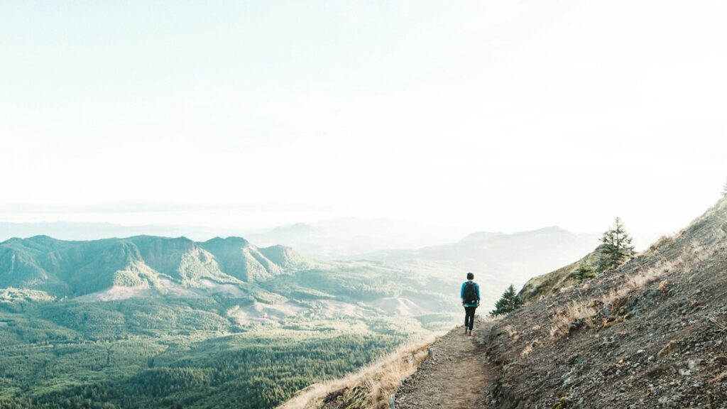 Man walking along a mountain trail at sunset