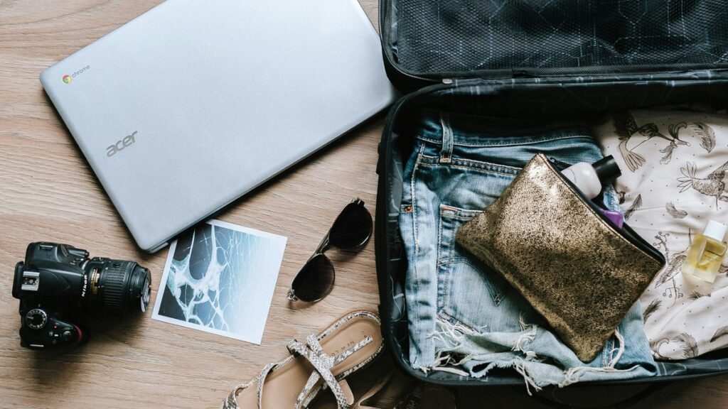 Travel items and clothing arranged around an open suitcase