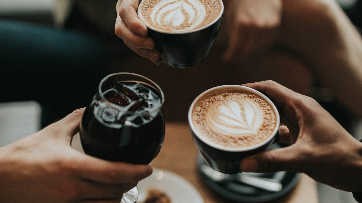 Hands holding coffee cups across a cafe table