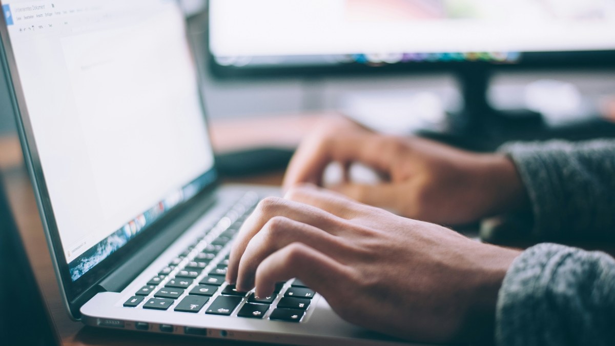 Hands typing on a laptop at a desk