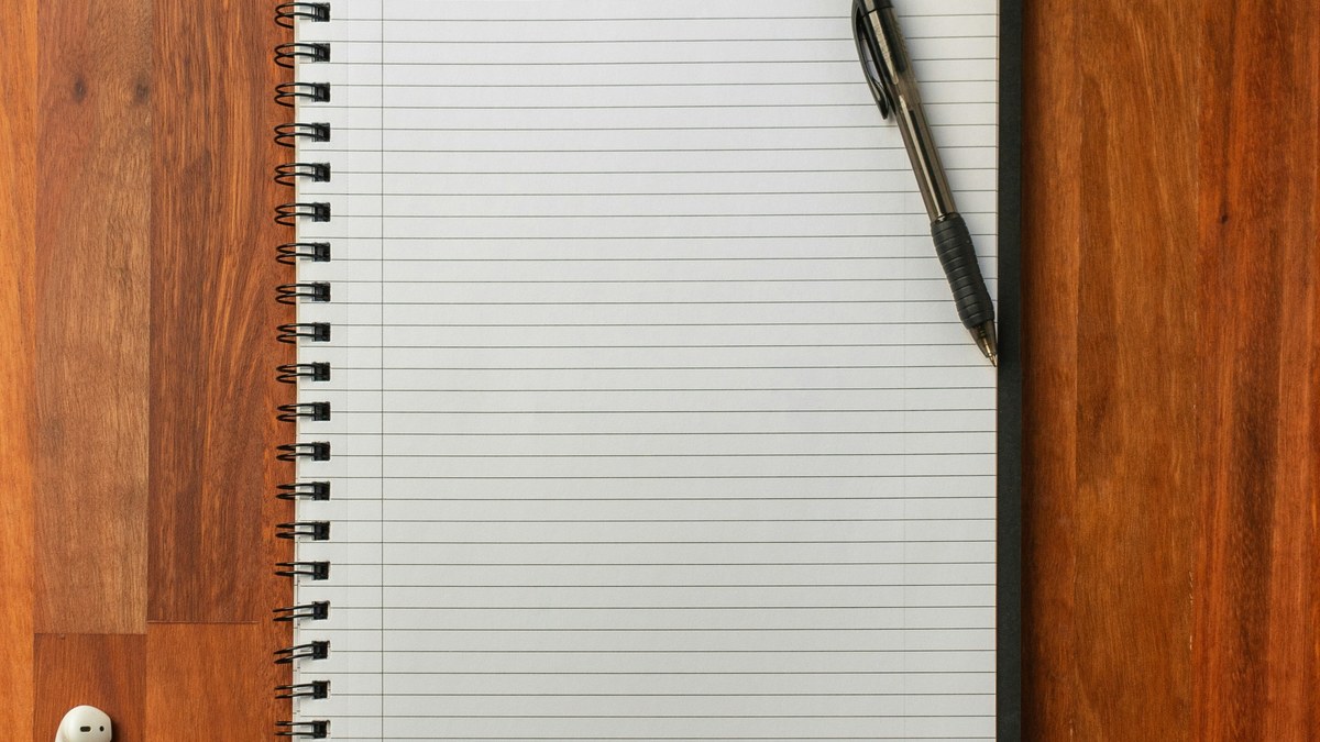 Lined notebook and pen on a wooden surface