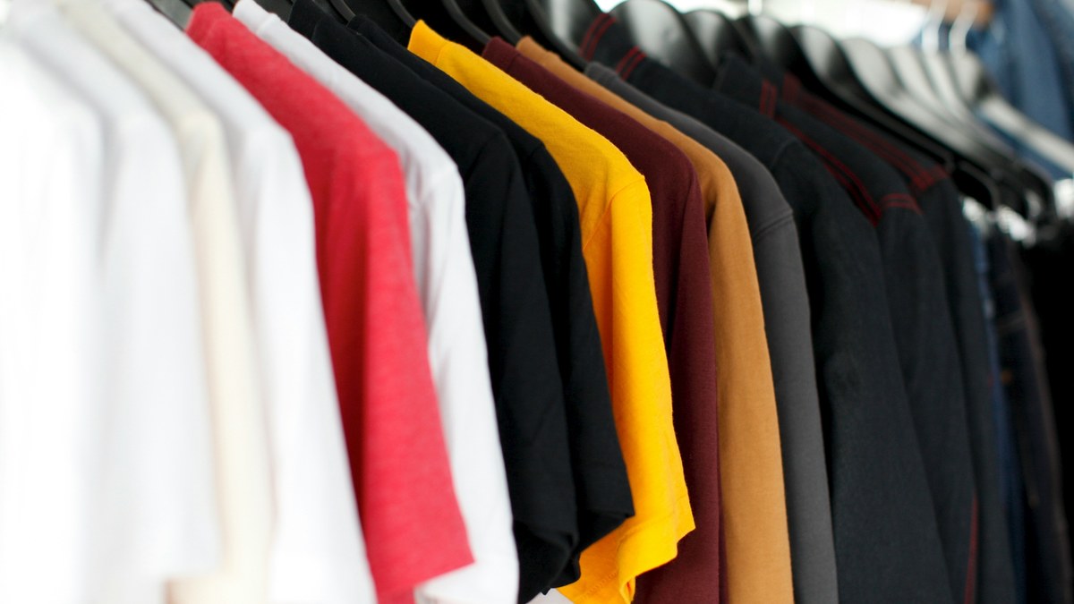Shirts in neutral and accent colors hanging on a rail