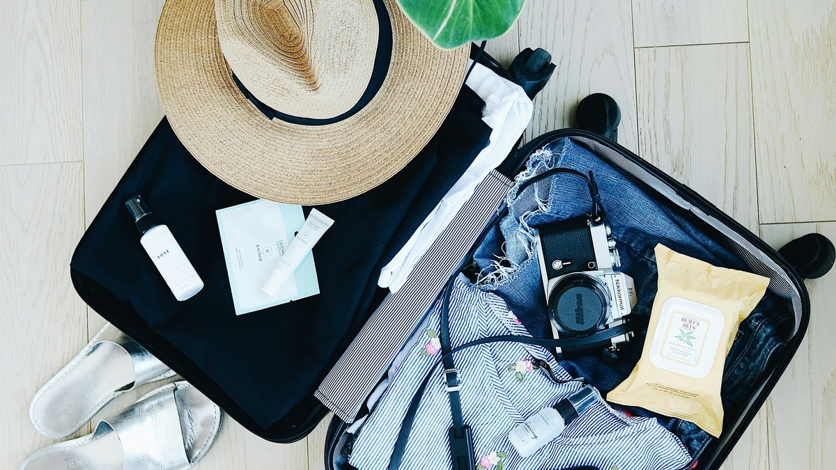 Open suitcase with travel clothes and accessories