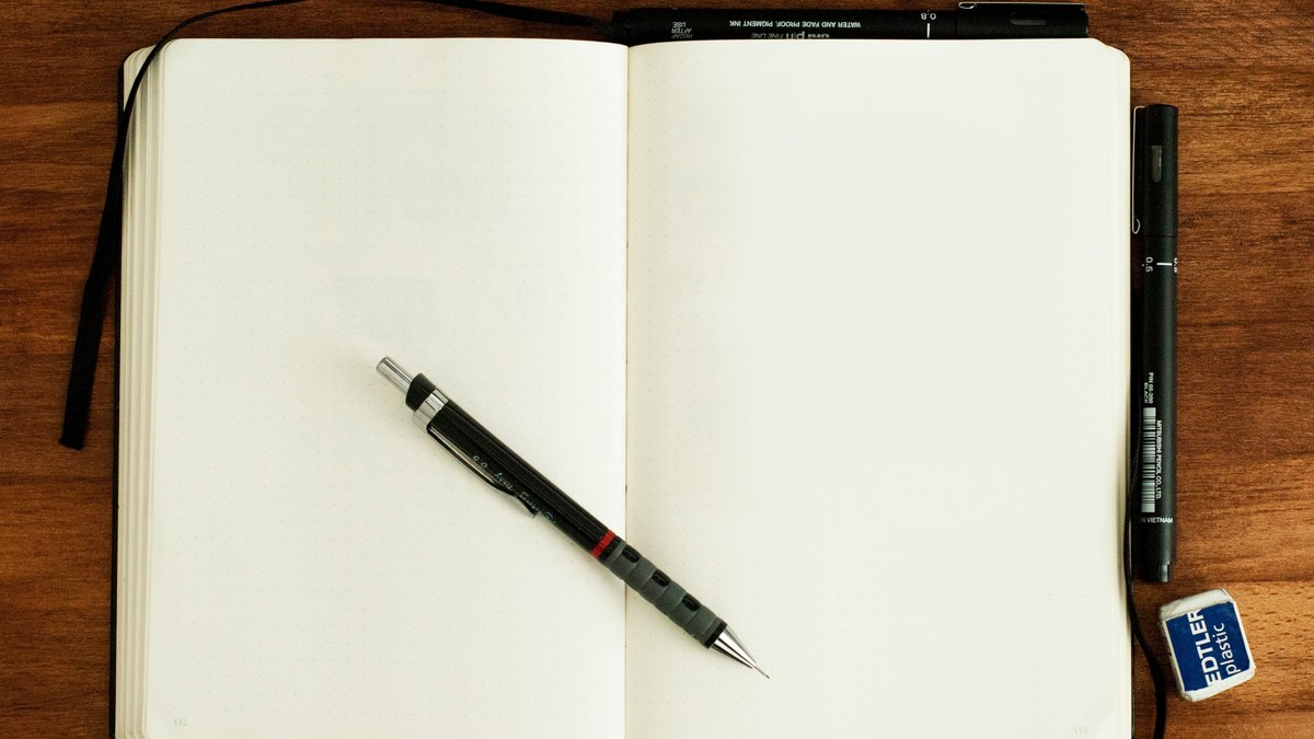 Open notebook with a pen resting across the pages