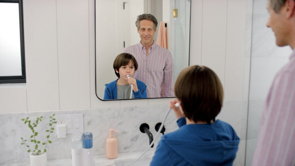 Man brushing his teeth in a bathroom mirror