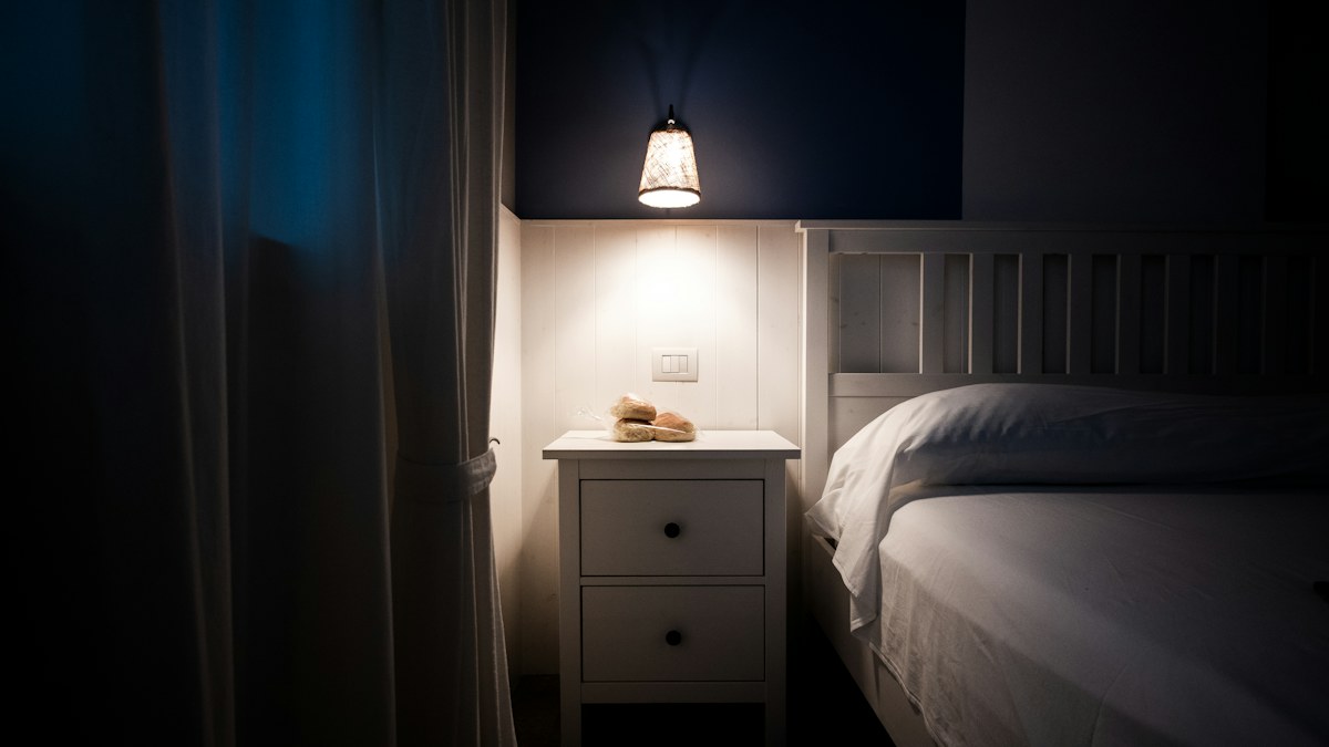 Bedside lamp and nightstand in a dark bedroom