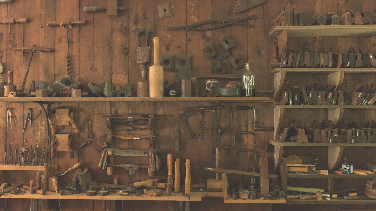Assorted hand tools arranged on a wooden shelf