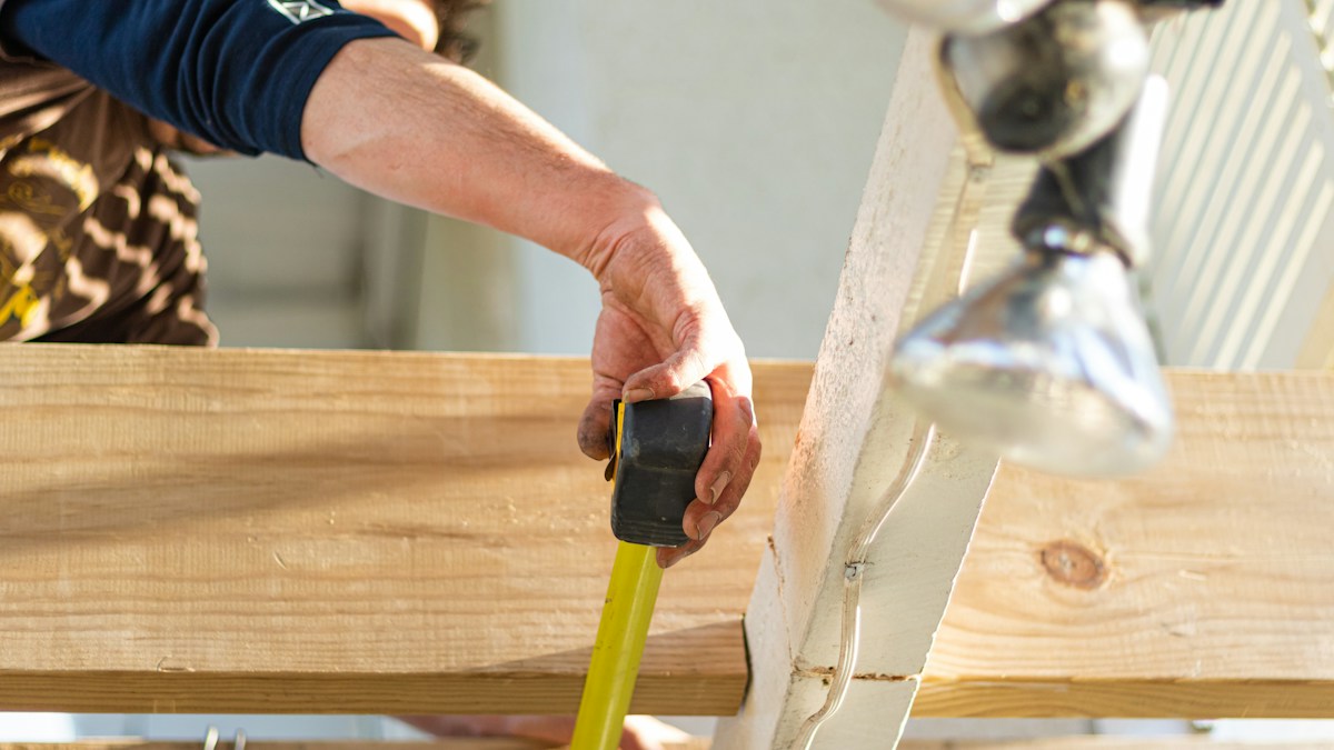 Builder measuring the space between structural wooden beams