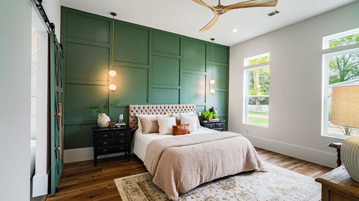 A paneled green feature wall behind a bed, illustrating painted raised-panel treatments