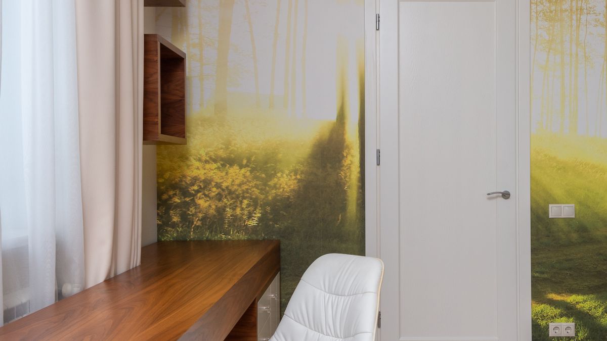An oversized forest landscape mural transforms a compact office wall into an immersive nature scene