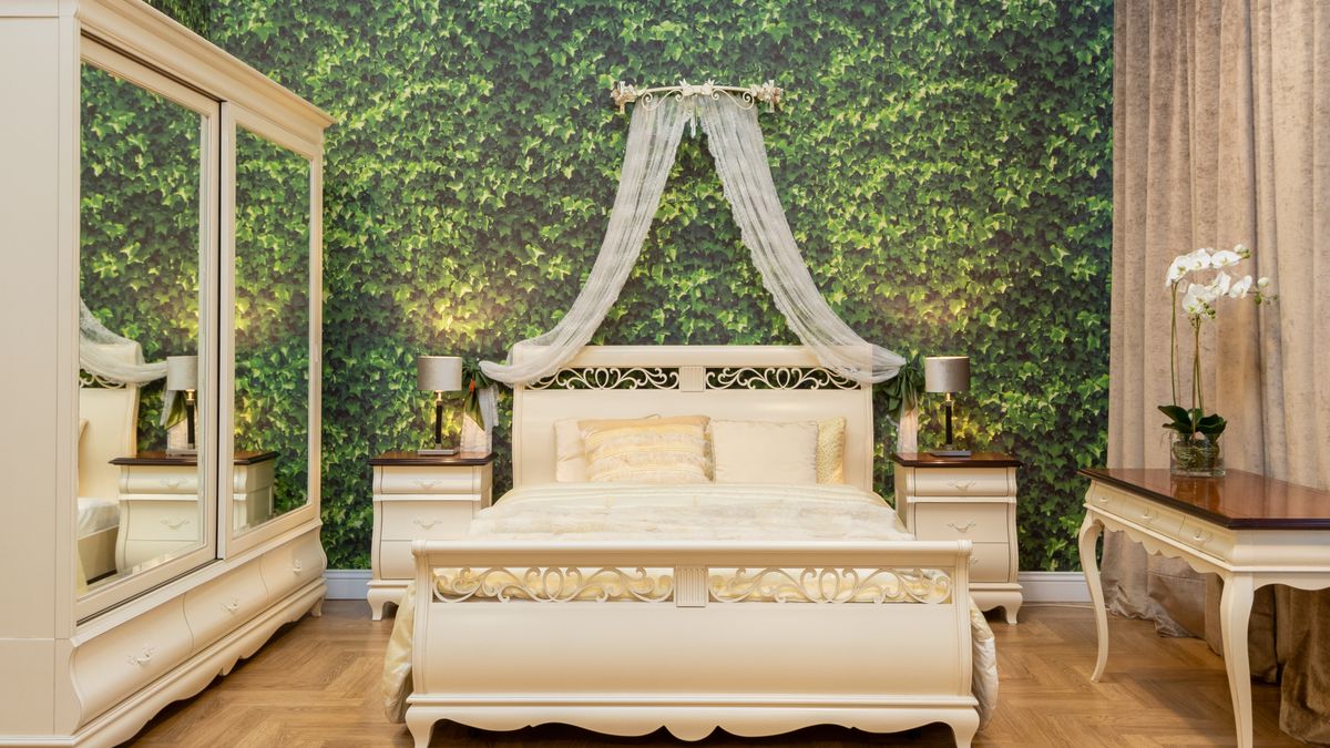 A saturated green bedroom wall provides a focal point behind pale furniture and bedding
