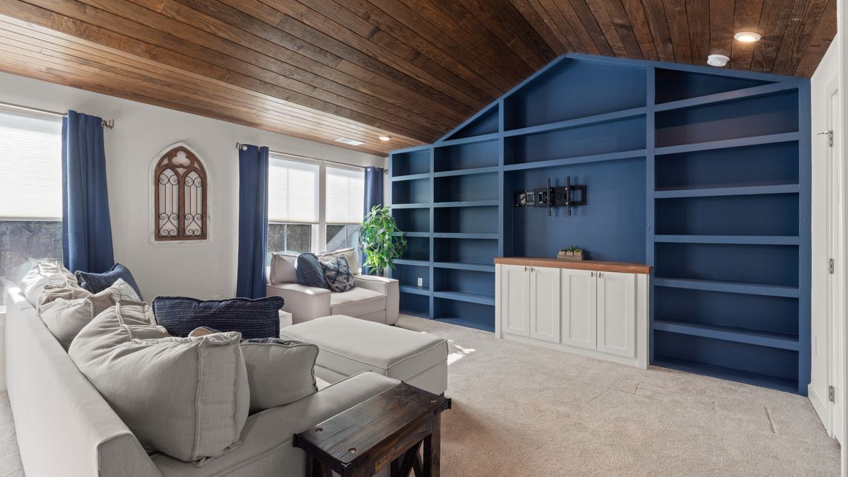 Blue built-in shelving makes the book and display wall a strong feature beside a neutral sofa