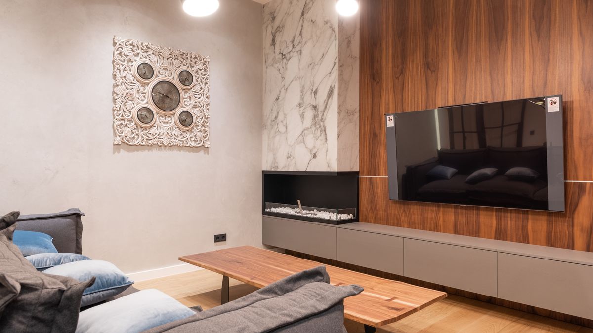 Television mounted on a wood-paneled media wall near a sofa