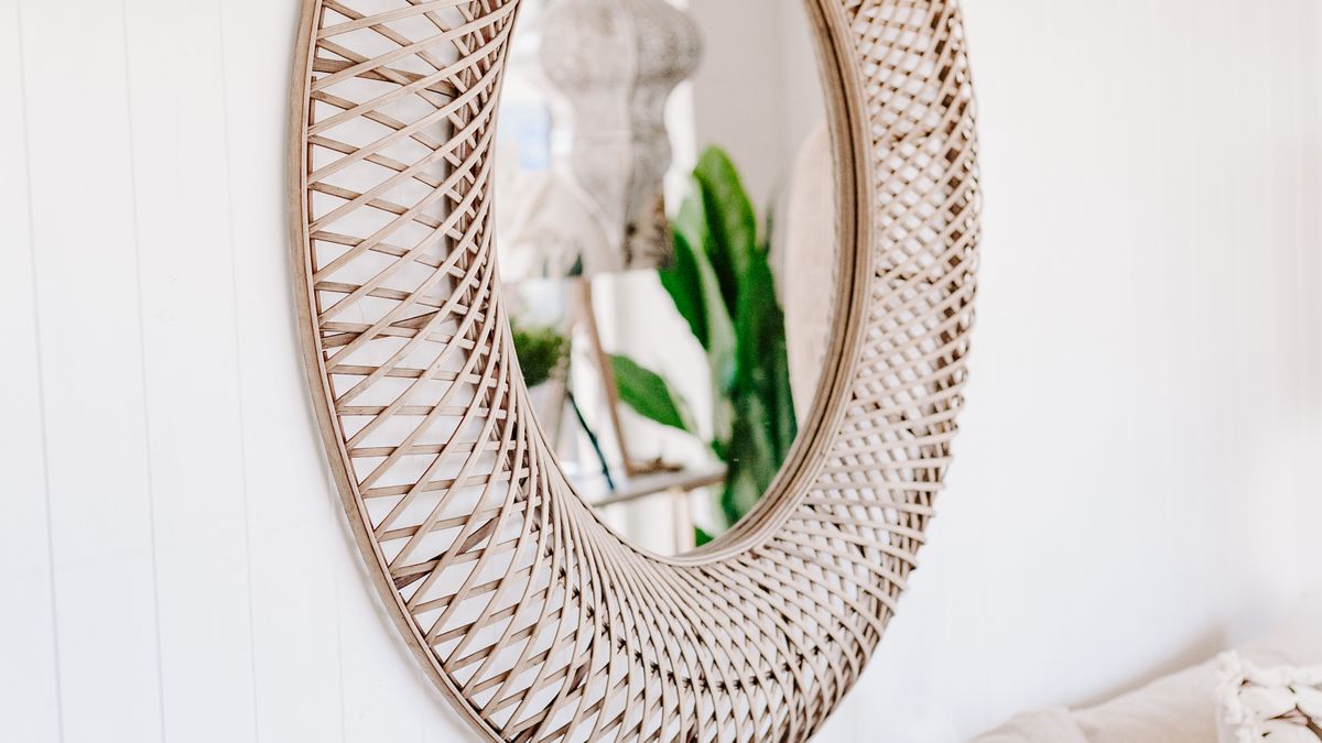 An understated oval mirror mounted above a neutral sofa