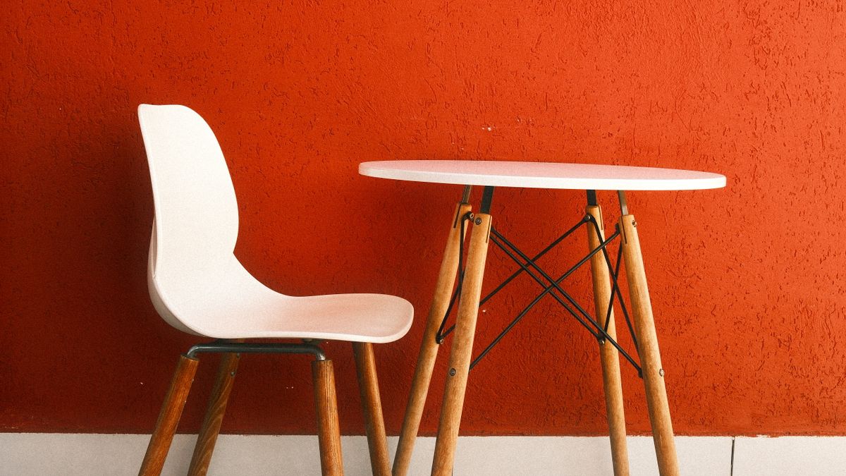 White chair and wooden table beside a vivid warm orange wall