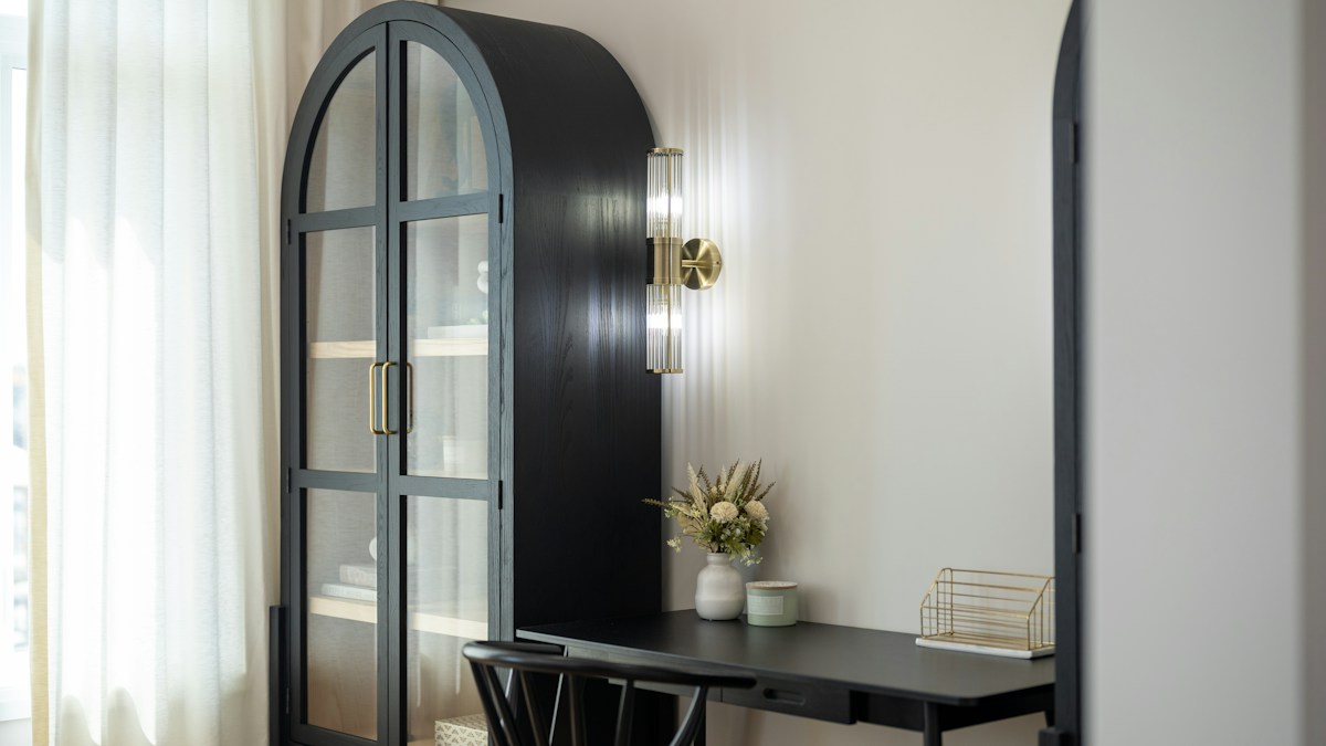 Black arched built-in niche with desk and wall light in a home office