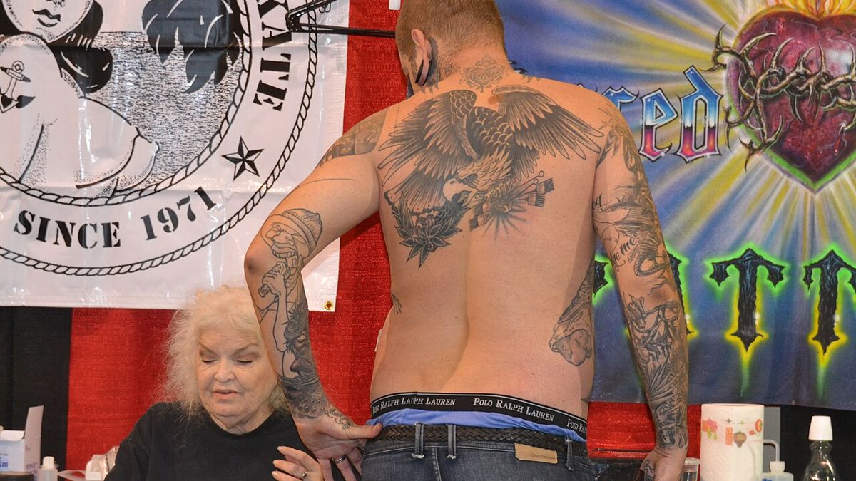 Large eagle with wings extended across a man's upper back at a tattoo convention