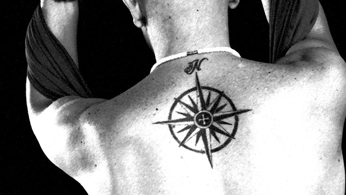 Black and white photograph showing a compass rose tattoo high between a man's shoulder blades