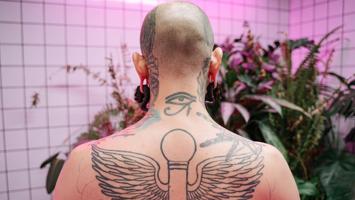 A man's upper-back wing tattoo illustrates a shoulder-spanning feather composition