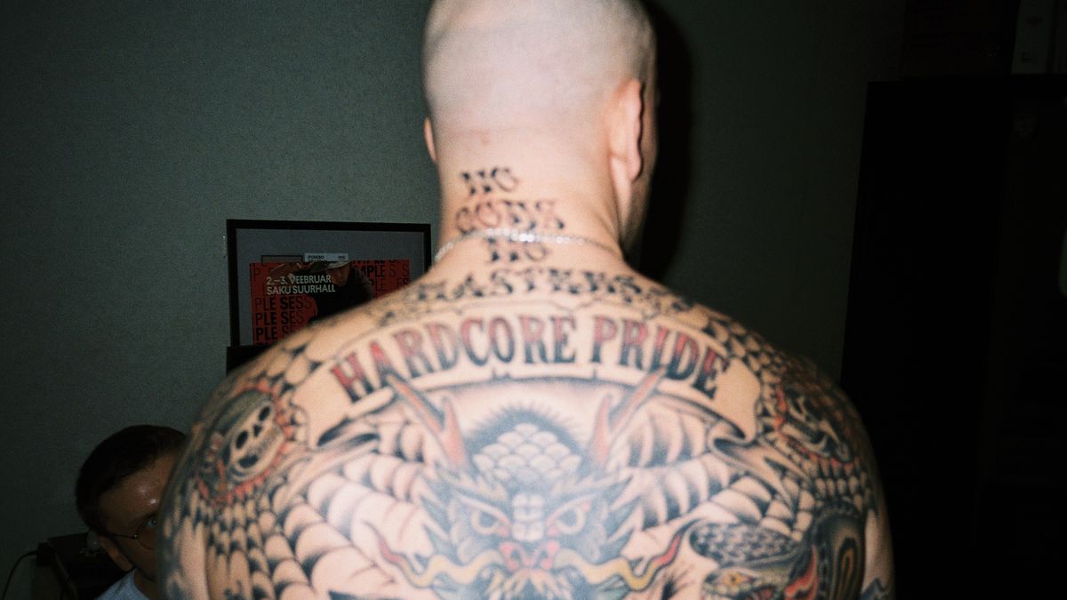 A man displays a full-back tattoo with colorful Japanese-style dragon imagery and accompanying motifs