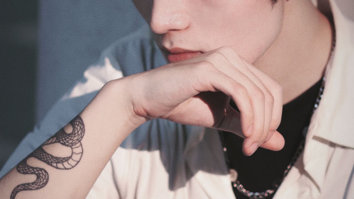 Black snake tattoo curving along a man's inner forearm