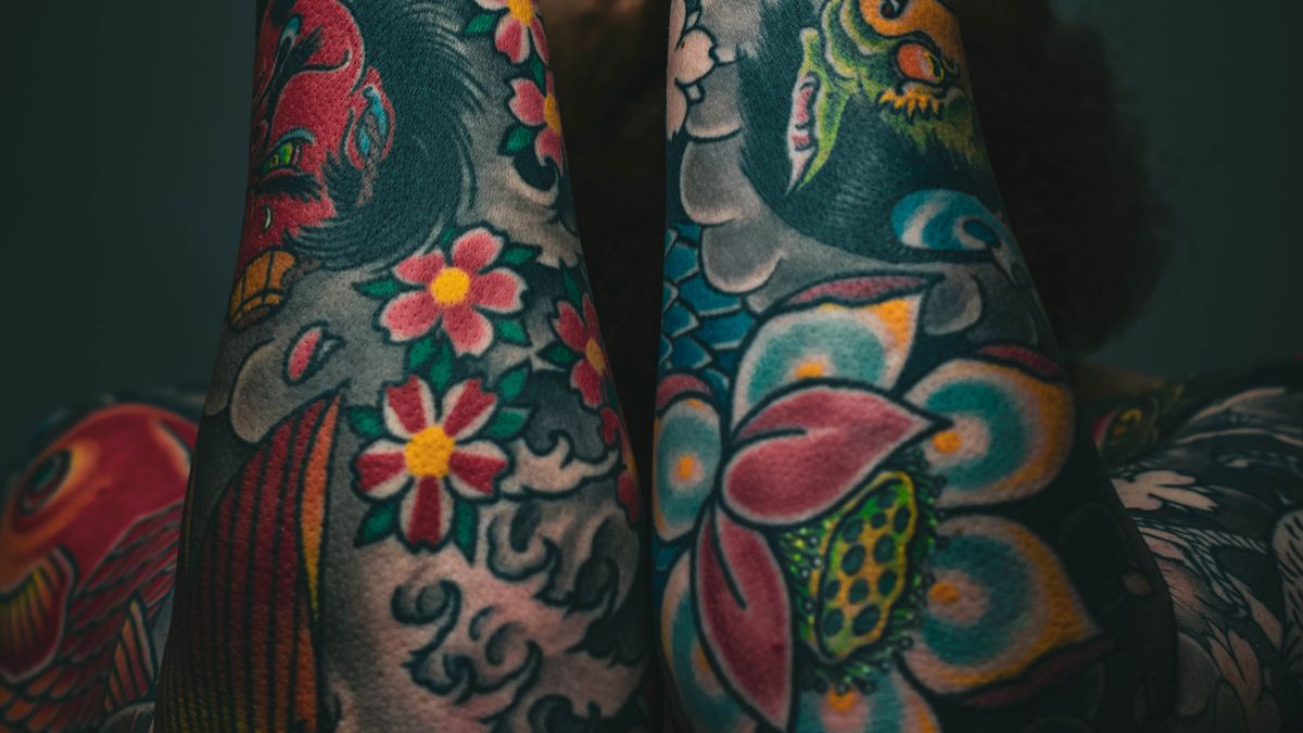 Colorful traditional Japanese-inspired floral tattoos across a man's forearms