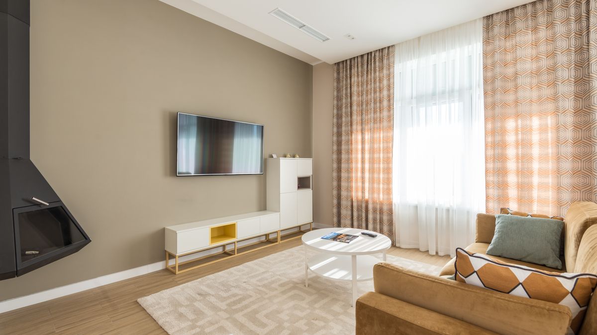 A large curtained window brightens an uncluttered living room