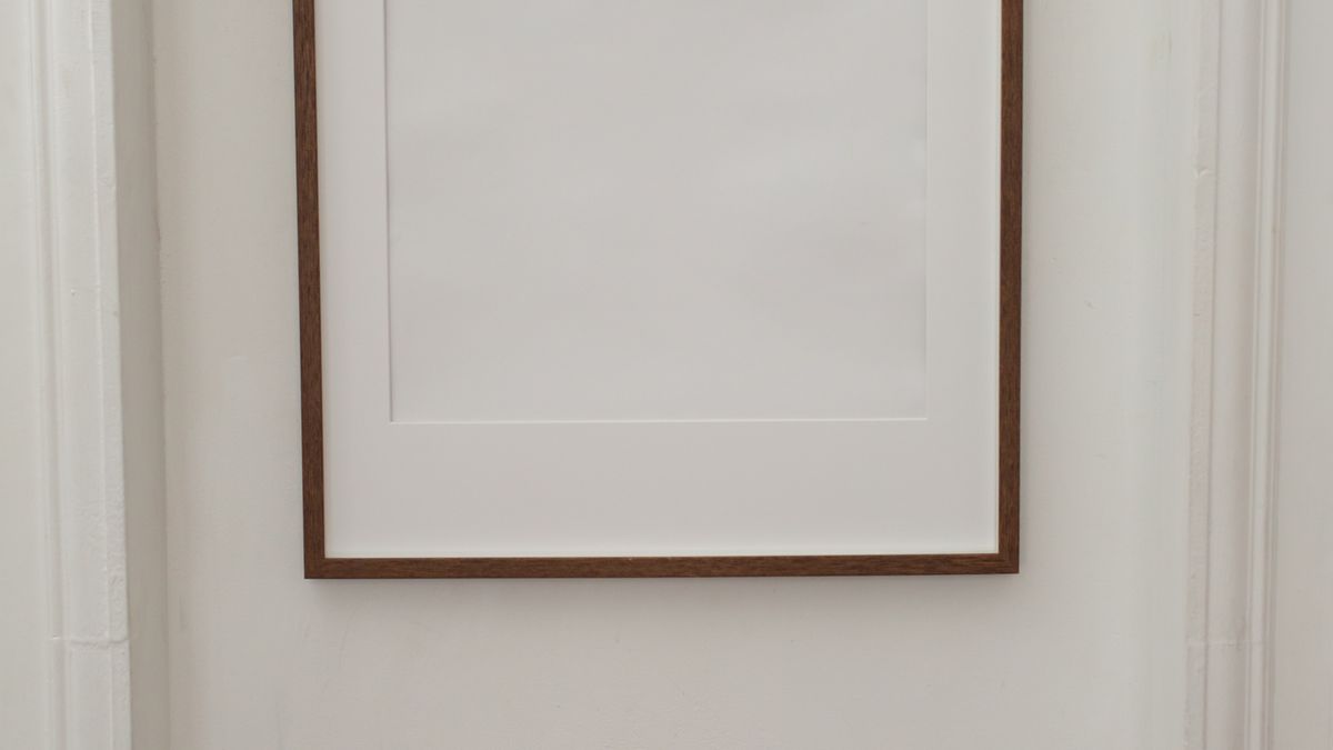 A largely blank apartment wall with one restrained picture frame
