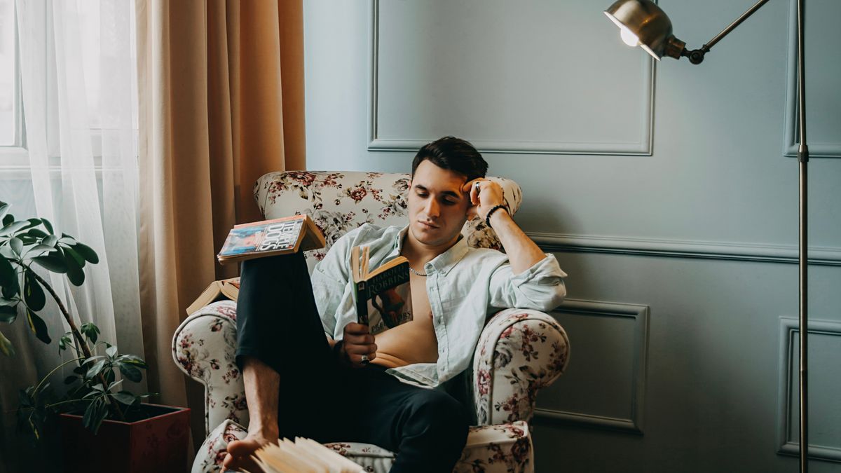 A reader beside a floor lamp in a comfortable armchair