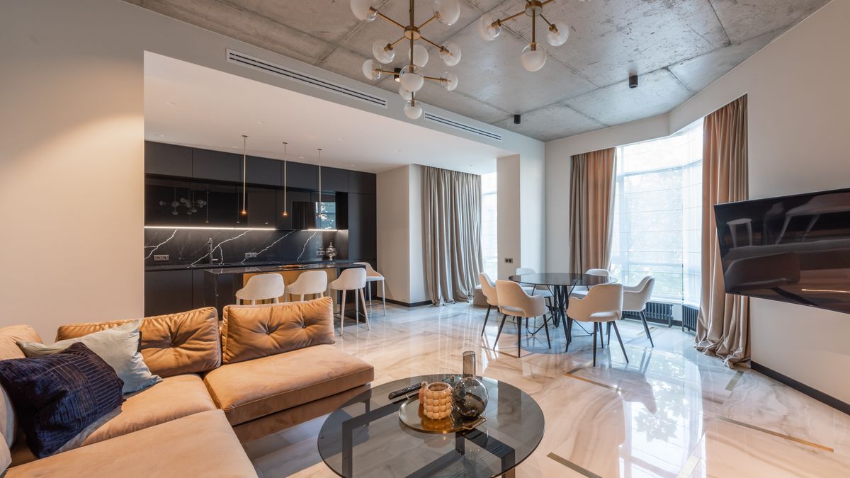 An open-plan studio layout leaves a central area available between compact seating, kitchen and dining furniture