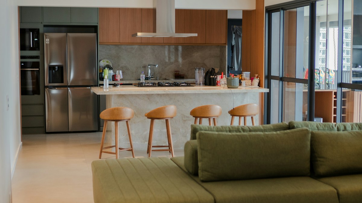 Open-plan living room with a green sofa and kitchen beyond