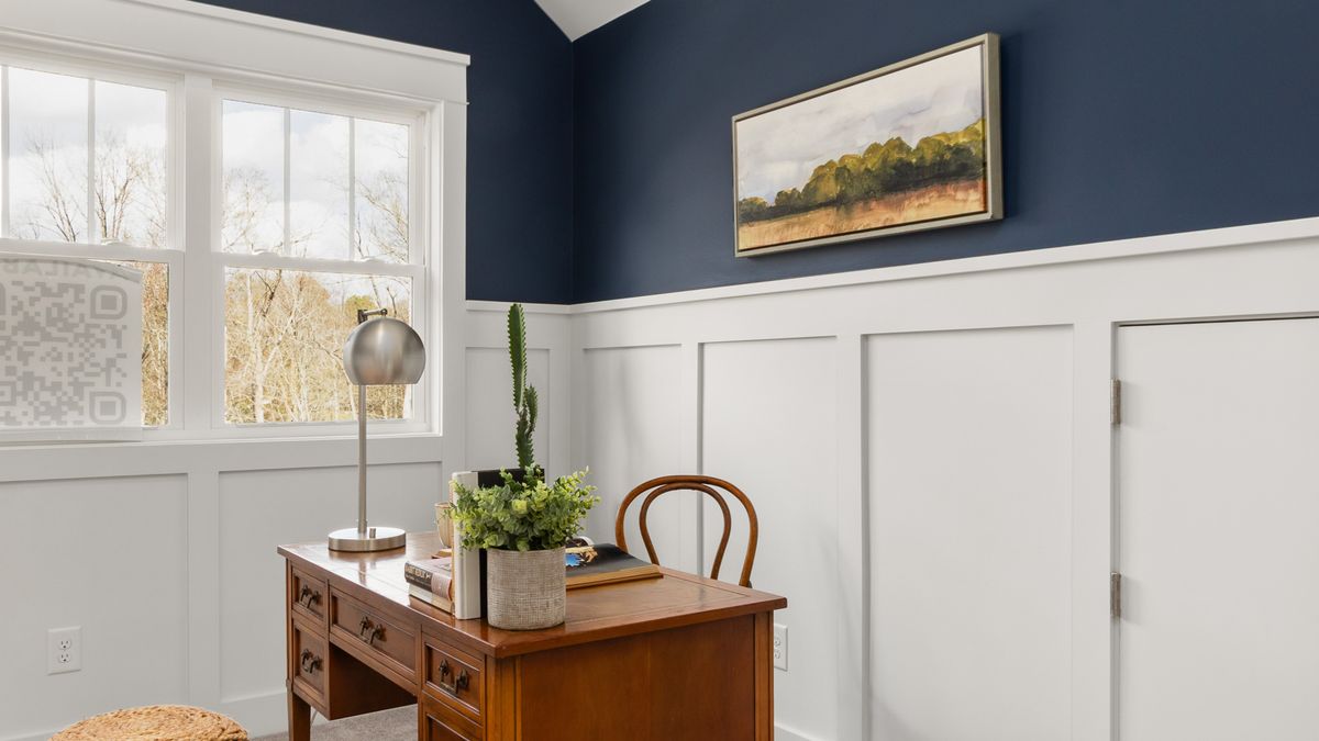 Small home office desk with artwork and a blue painted wall