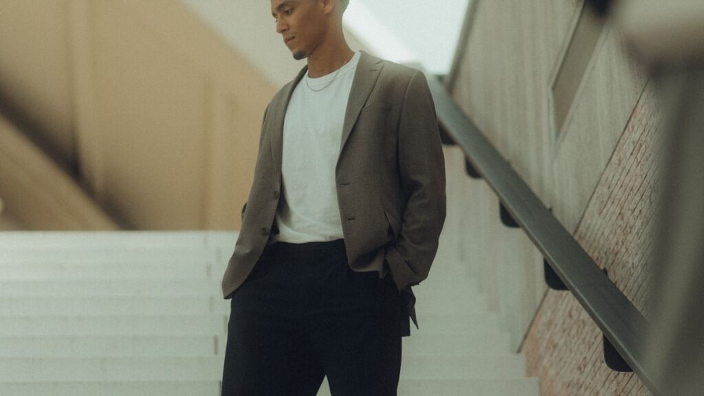 Man wearing a gray jacket and dark trousers on outdoor stairs