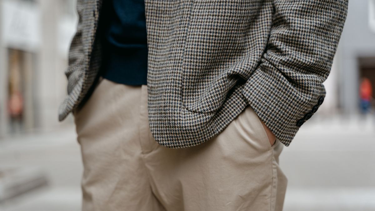 Close-up of a man's checkered blazer and tan trousers outdoors