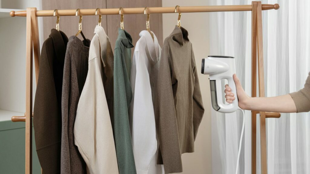 Garment steamer beside hanging clothing