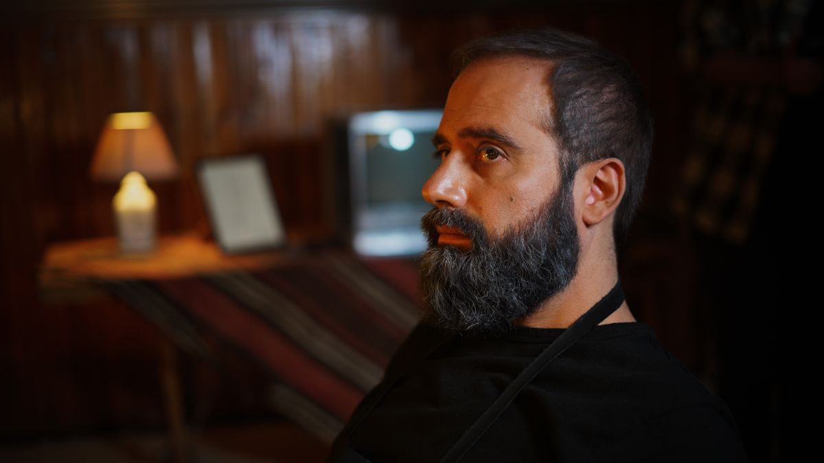 Close-up profile of a bearded man in warm indoor light